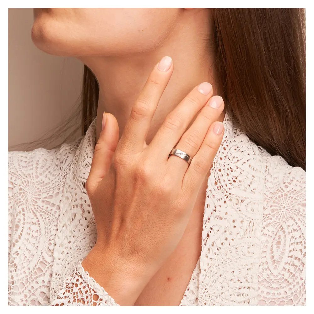 Längsmatte Eheringe aus Weißgold mit Rille und Diamanten auf Hand am Gesicht