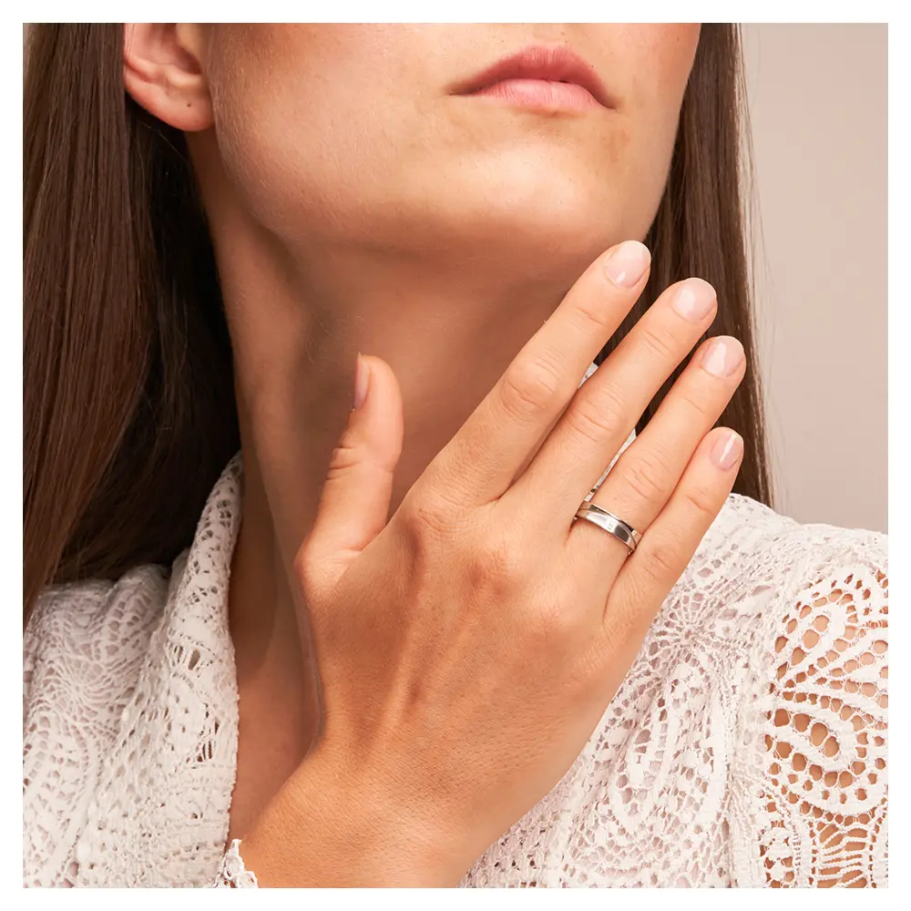 Eheringe aus Weißgold konkav und matt mit Diamanten auf Hand am Gesicht