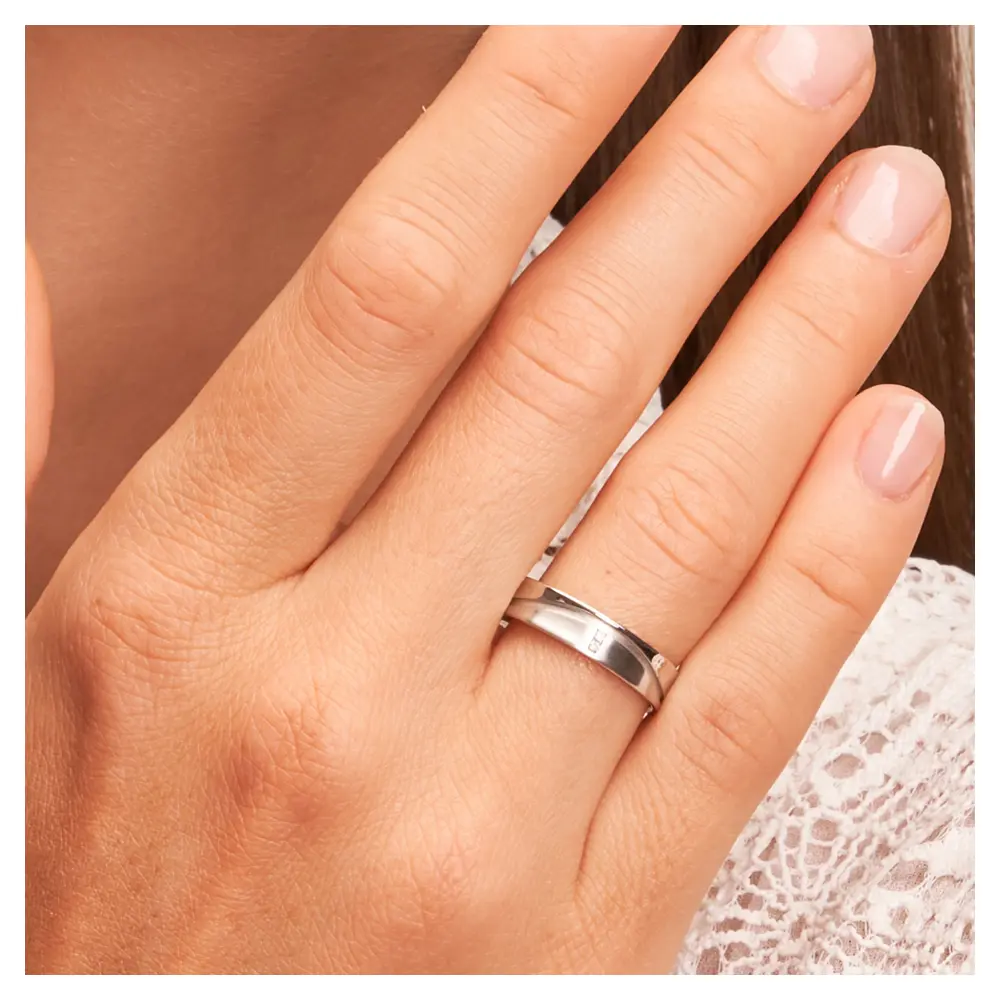 Eheringe aus Weißgold konkav und matt mit Diamanten auf Hand am Gesicht im Zoom