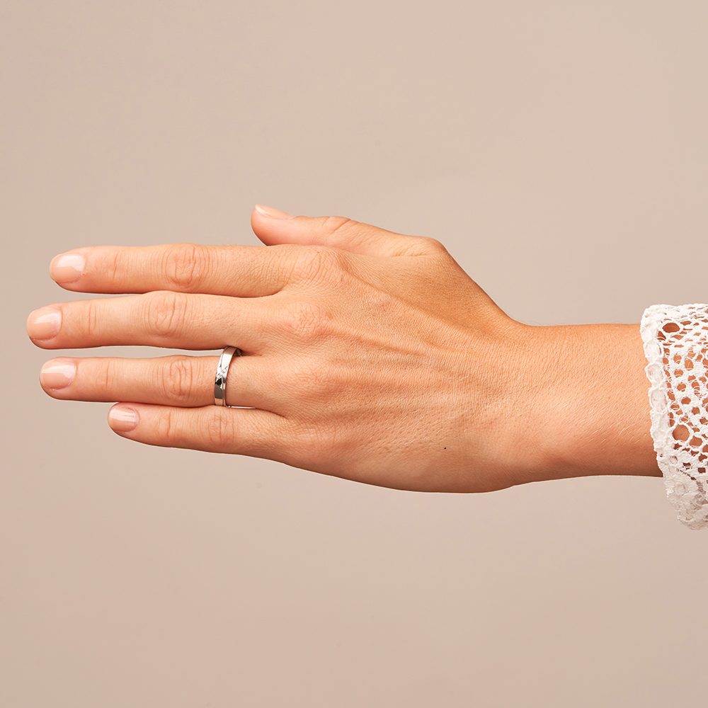Eheringe aus Platin mit geschwungener Rille und 3 Diamanten auf Hand