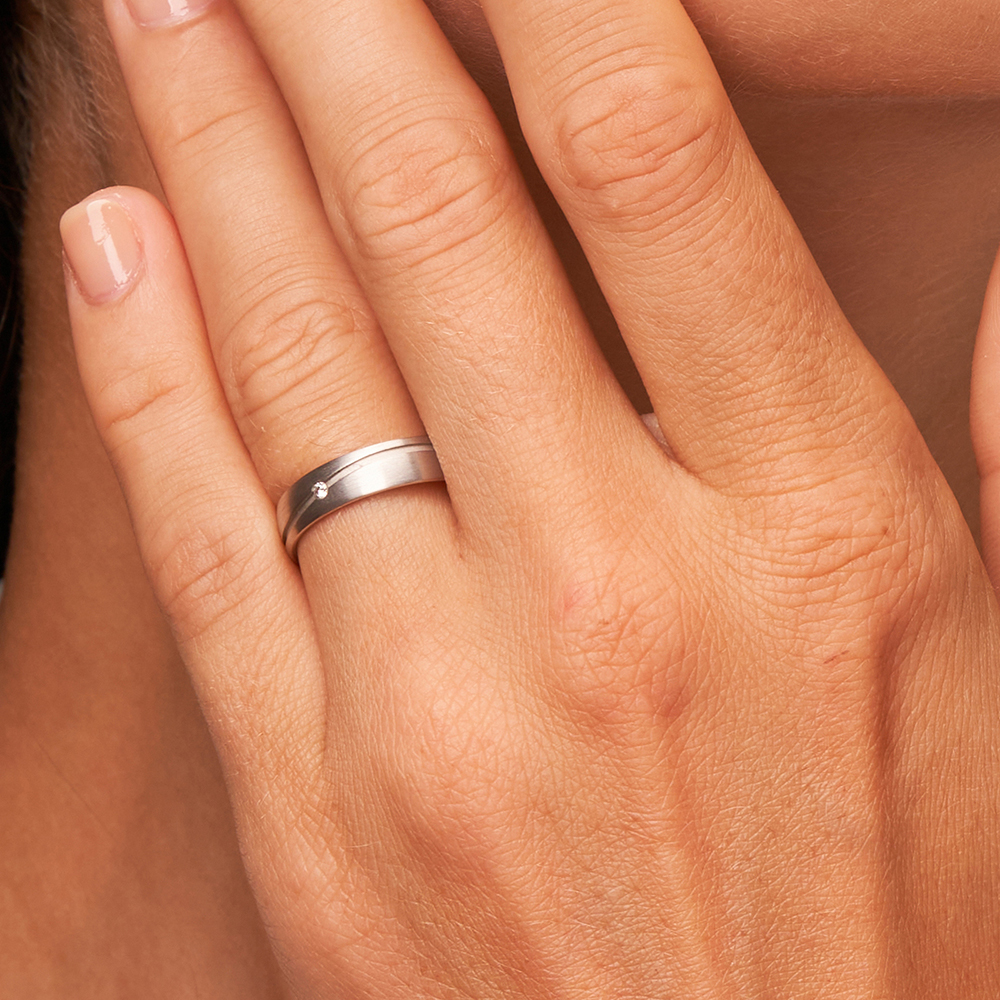 Längmattierter Weissgold Trauring mit Diamanten in gewellter Rille auf Hand in Nahaufnahme