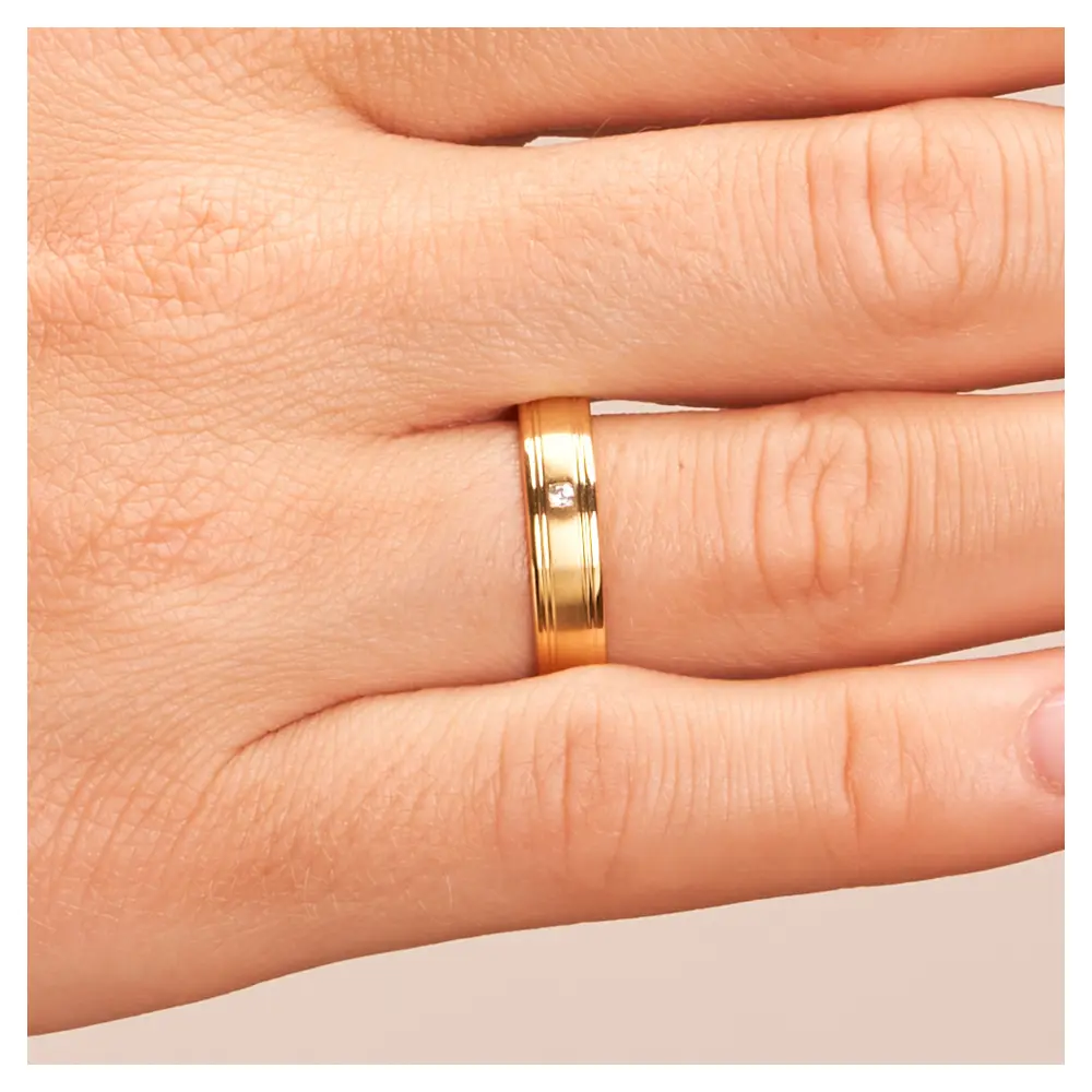 Matte Gelbgold Eheringe mit polierten Rillen und Diamanten auf Hand im Zoom