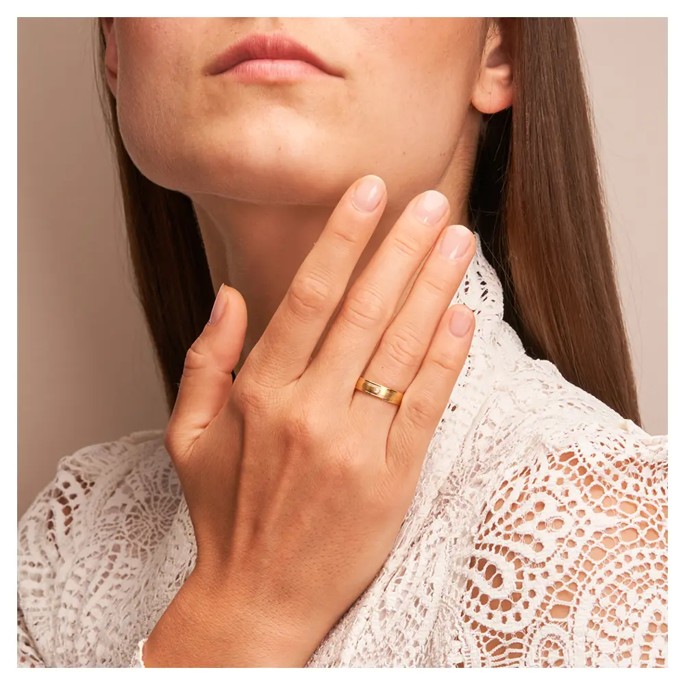 Matte Gelbgold Eheringe mit polierten Rillen und Diamanten auf Hand am Gesicht