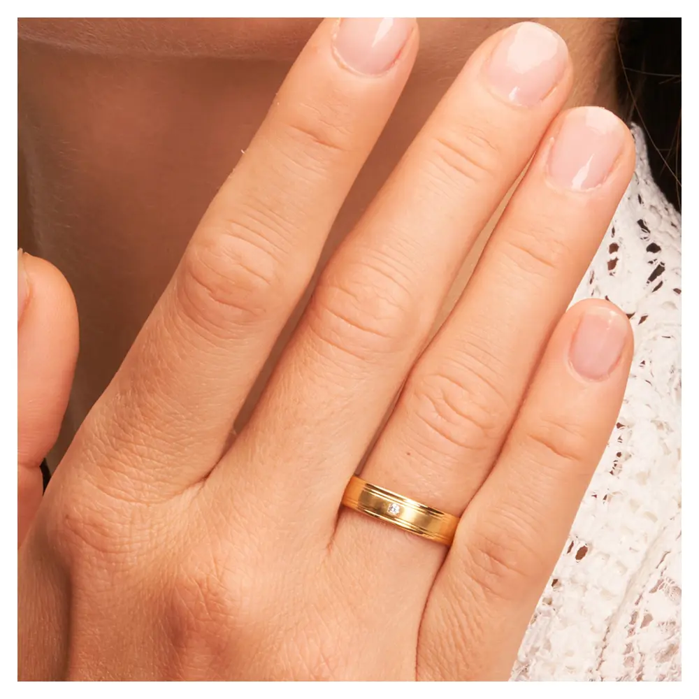 Matte Gelbgold Eheringe mit polierten Rillen und Diamanten auf Hand am Gesicht im Zoom