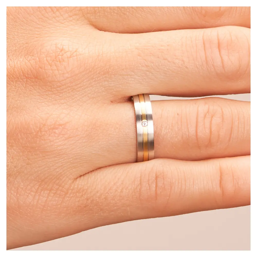 Weißgold und Gelbgold Eheringe längsmattiert mit Diamanten auf Hand im Zoom