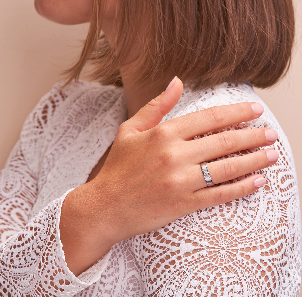 Eheringe aus Platin mit Diamanten und Längsmattierung auf Hand an Schulter