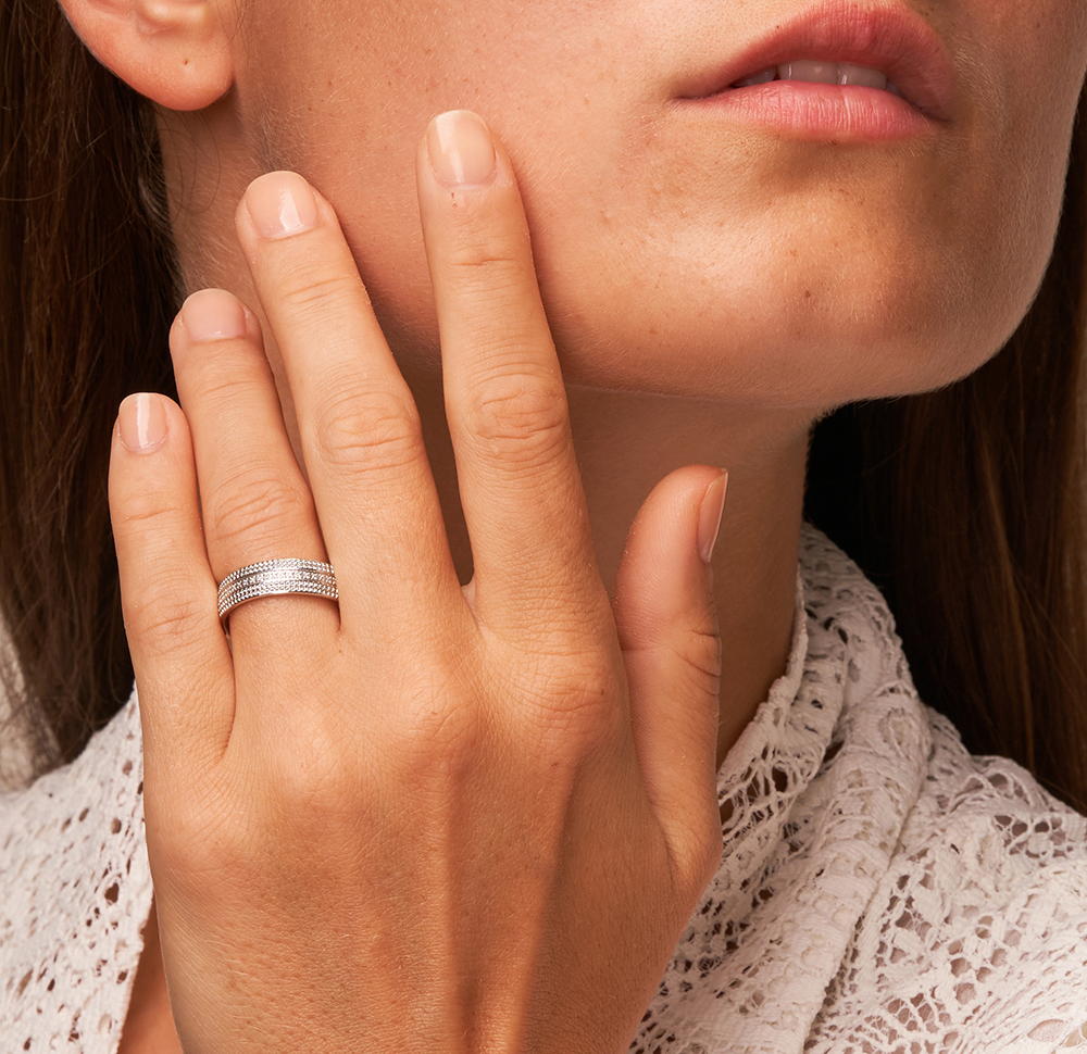 Polierter Platin Ehering mit Millgriff Design und Diamantenband auf Hand am Gesicht