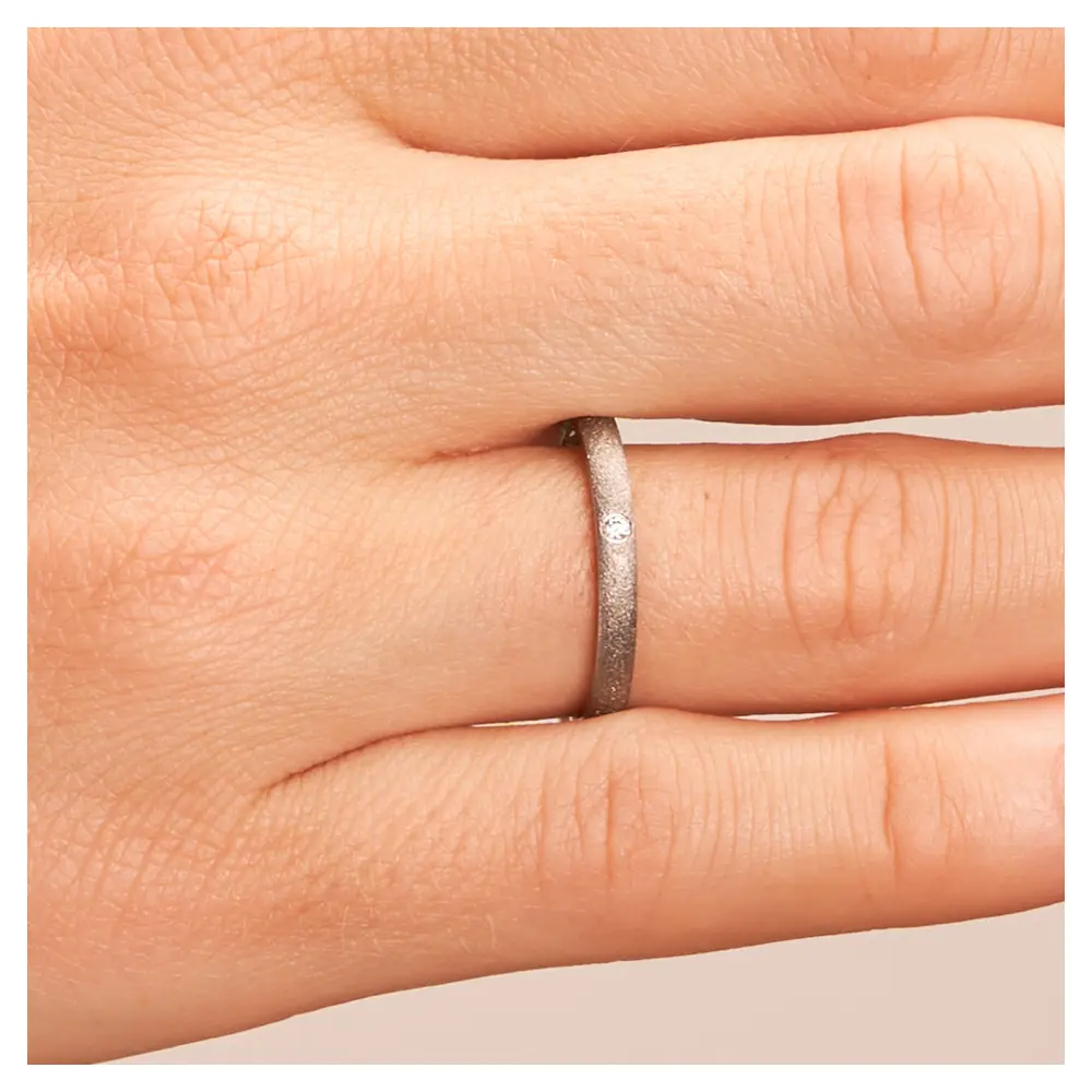 Sandmattierter schmaler Vorsteckring aus Titan mit Diamant in 0,025 Karat auf Hand im Zoom