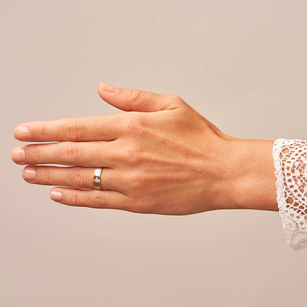 Eheringe aus Weißgold mit Rändern aus Gelbgold mit 3 Diamanten in Kanalfassung auf Hand