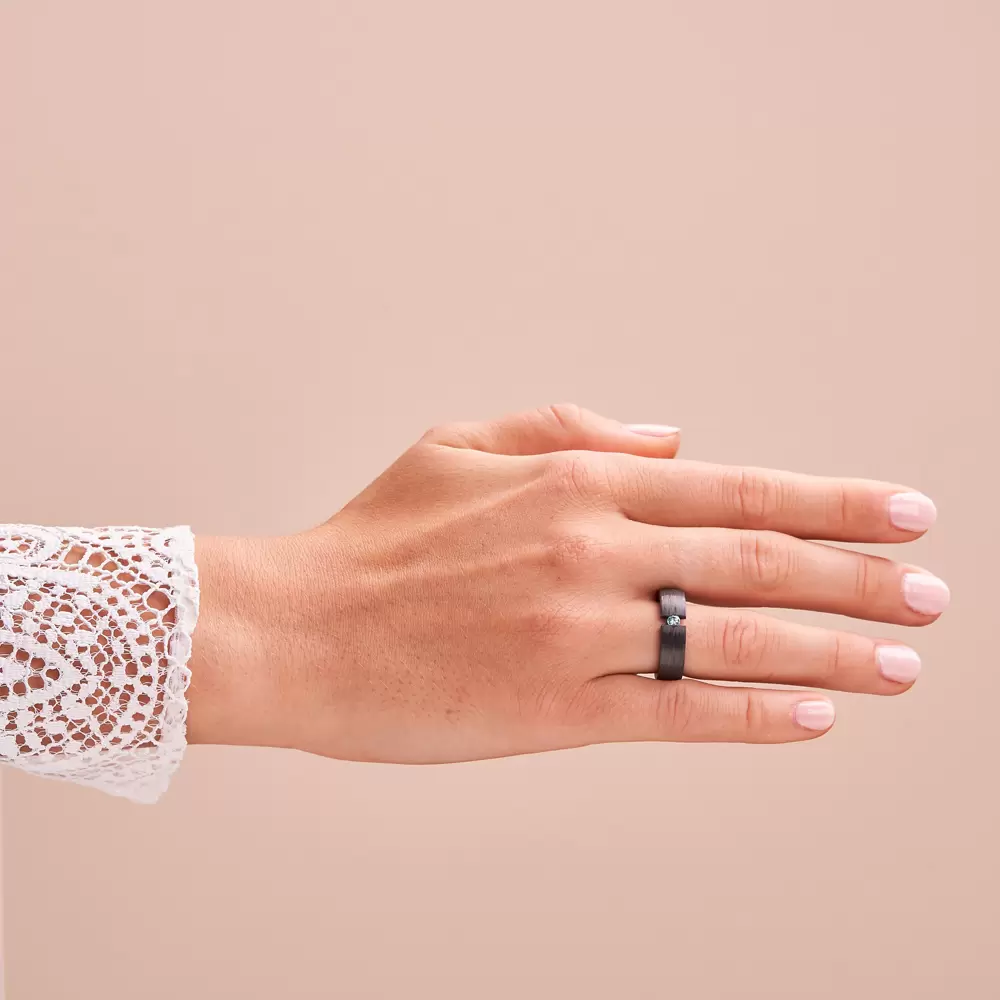 Carbon Ehering mit eingespanntem blauen Diamanten auf Hand