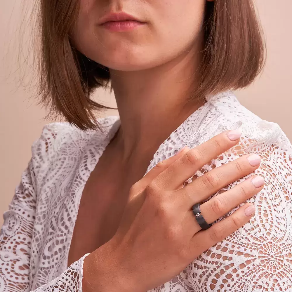 Ehering aus Carbon mit cognacfarbenen Diamanten in Spannfassung auf Hand an Schulter