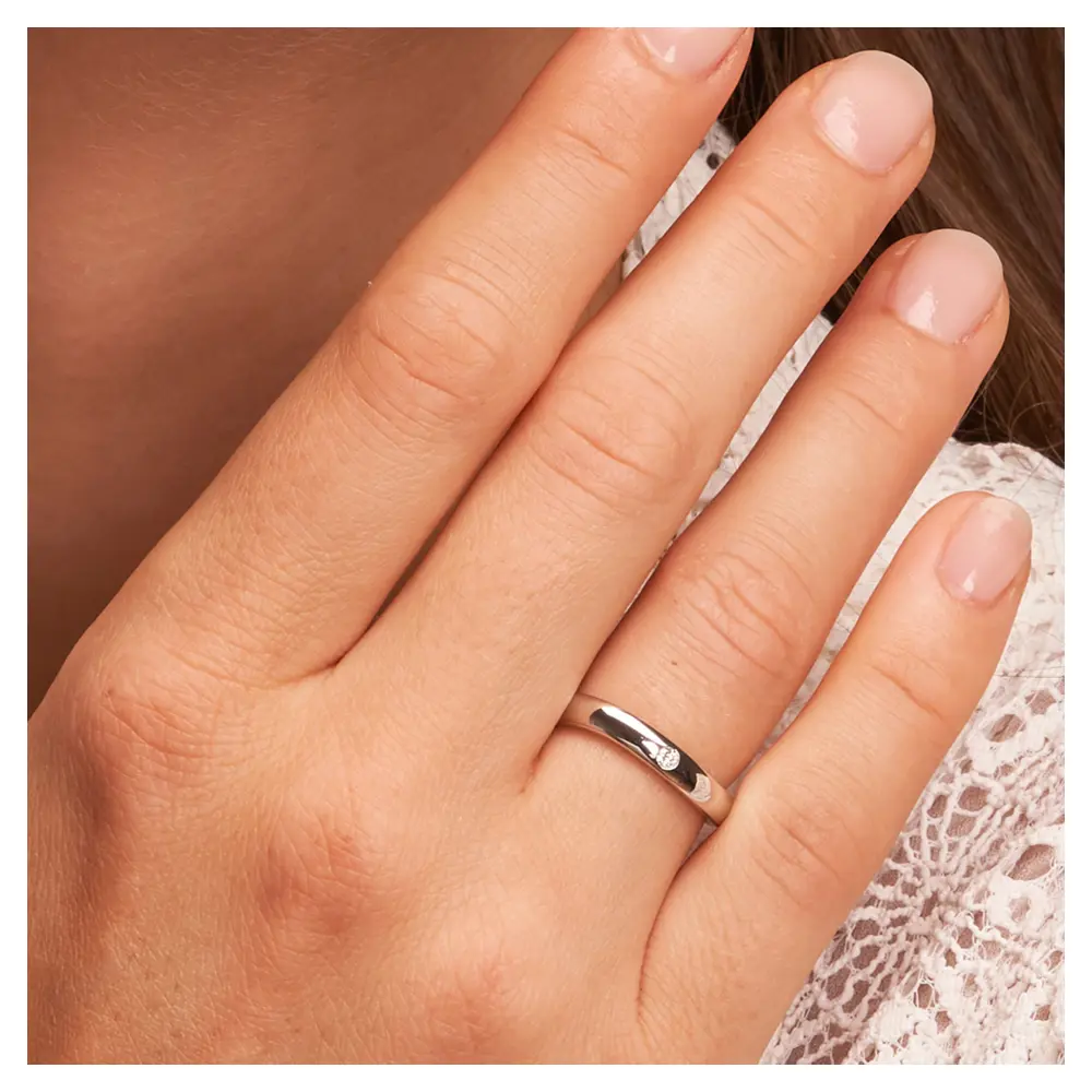 Polierte Trauringe aus Silber 925 mit Rhodinierung und Labor-Diamanten auf Hand am Gesicht im Zoom