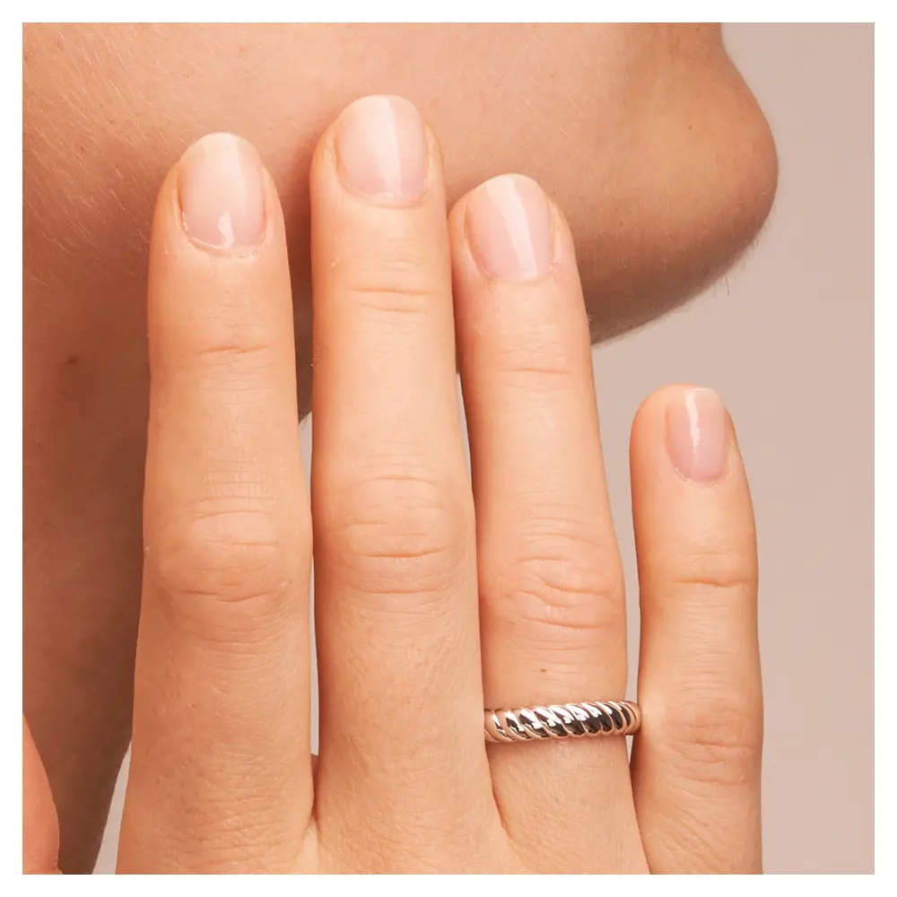 Trauringe aus rhodiniertem Silber 925 in gekordeltem Design auf Hand am Gesicht im Zoom