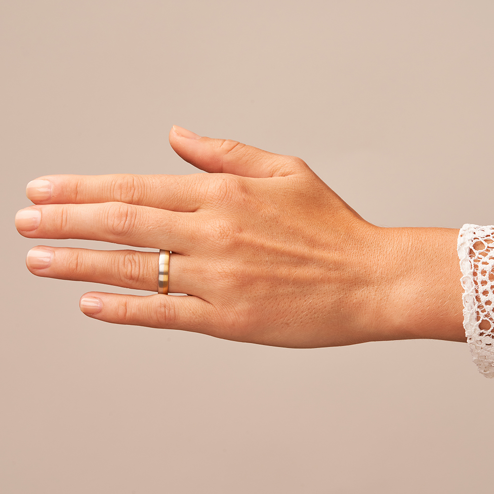 Mattierte Eheringe aus Gelbgold und Platin auf Hand