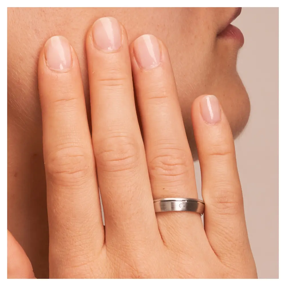 Trauringe aus platiniertem Silber 925 mit Diamanten und seitlicher Rille auf Hand am Gesicht im Zoom