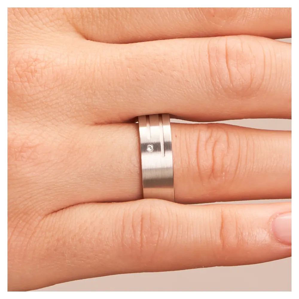 Breite Trauringe aus Silber 925 platiniert mit Diamanten und Rillen auf Hand im Zoom