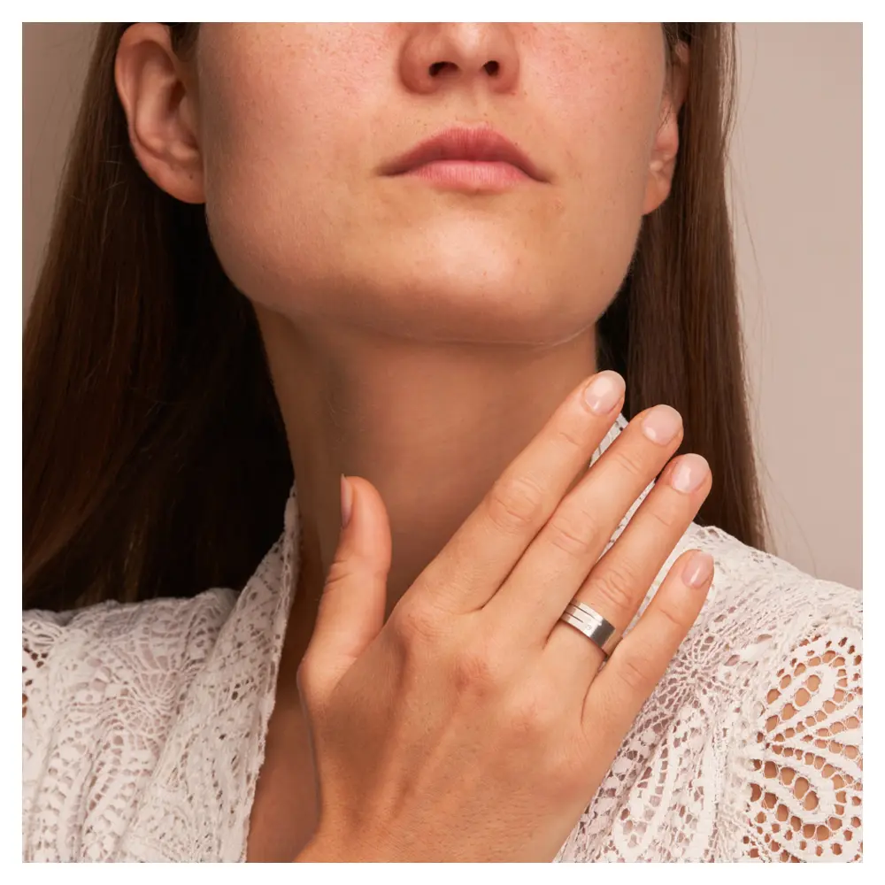 Breite Trauringe aus Silber 925 platiniert mit Diamanten und Rillen auf Hand am Gesicht