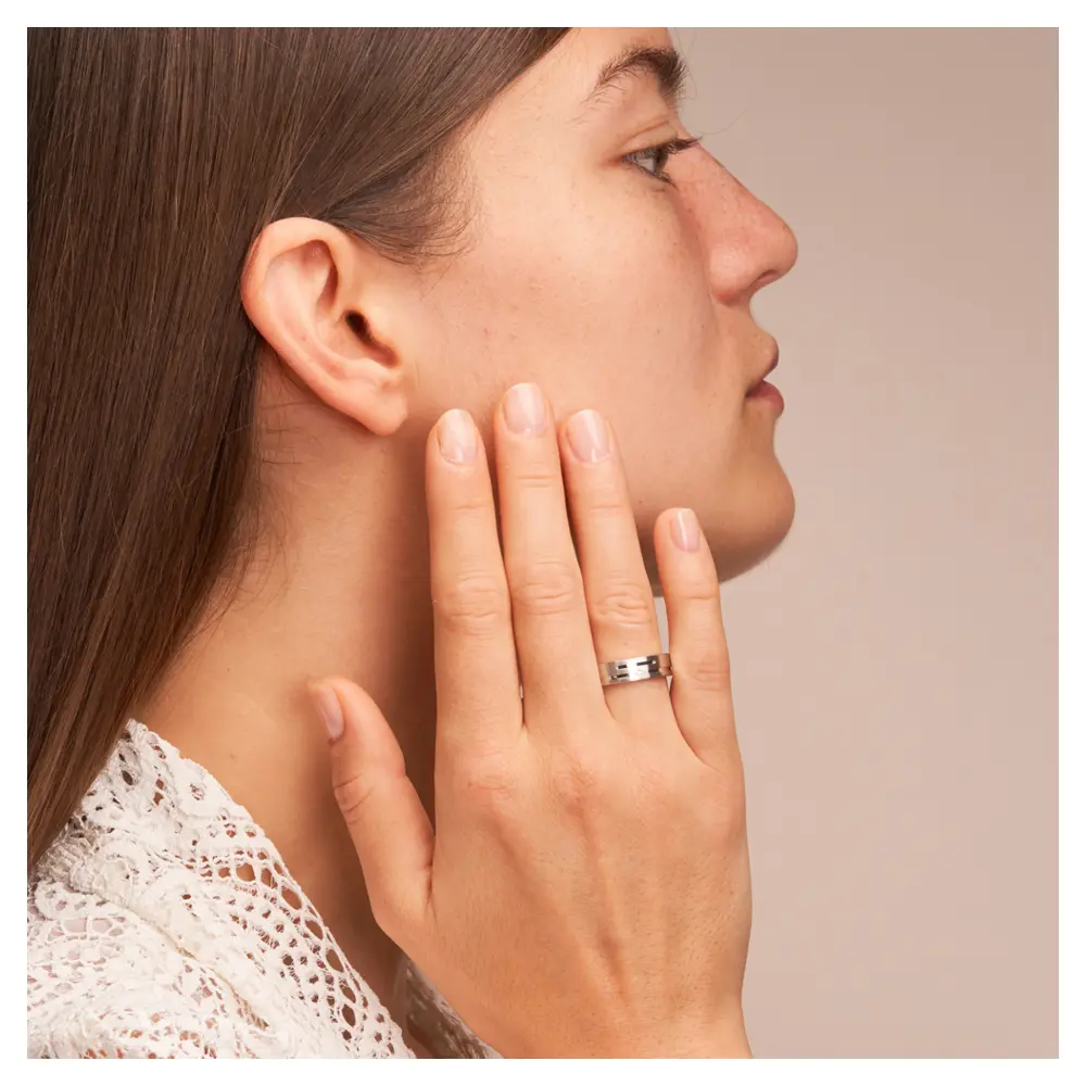 Eheringe aus platiniertem Silber 925 mit Rillenmuster und Diamanten auf Hand am Gesicht