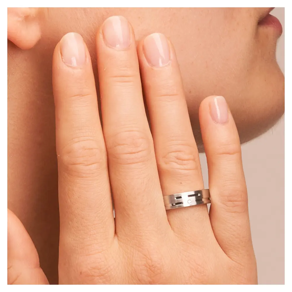 Eheringe aus platiniertem Silber 925 mit Rillenmuster und Diamanten auf Hand am Gesicht im Zoom
