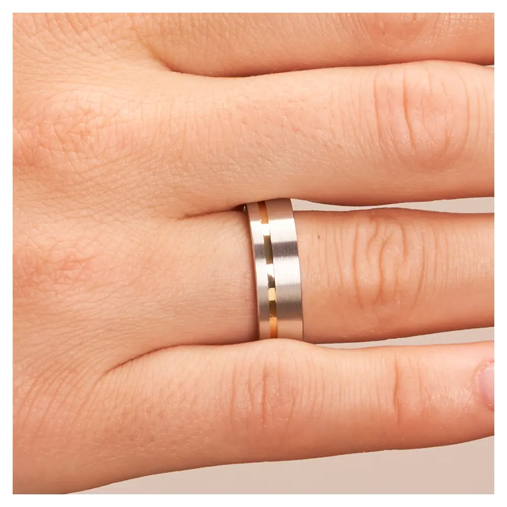 Trauringe aus platiniertem Silber mit Gelbgoldstreifen auf Hand im Zoom