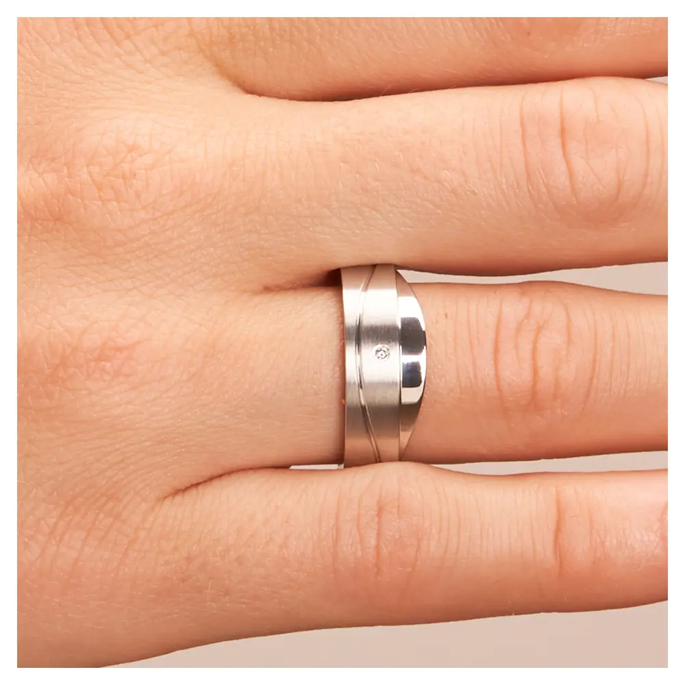 Asymmetrische Eheringe aus platiniertem Silber mattiert mit Diamanten auf Hand im Zoom