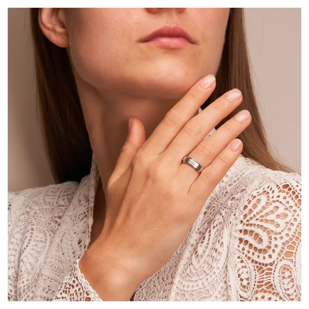 Trauringe aus platiniertem Silber 925 im wellenförmigen Design mit Diamanten auf Hand am Gesicht