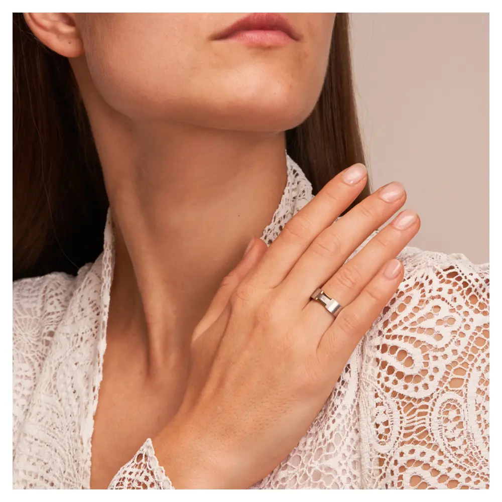 Trauringe aus platiniertem Silber 925 mit 14K Gelbgold Rillen und Diamanten auf Hand am Gesicht