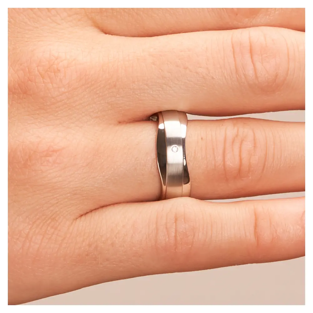 Trauringe aus Silber 925 platiniert mit welligem Rand und Diamant auf Hand im Zoom