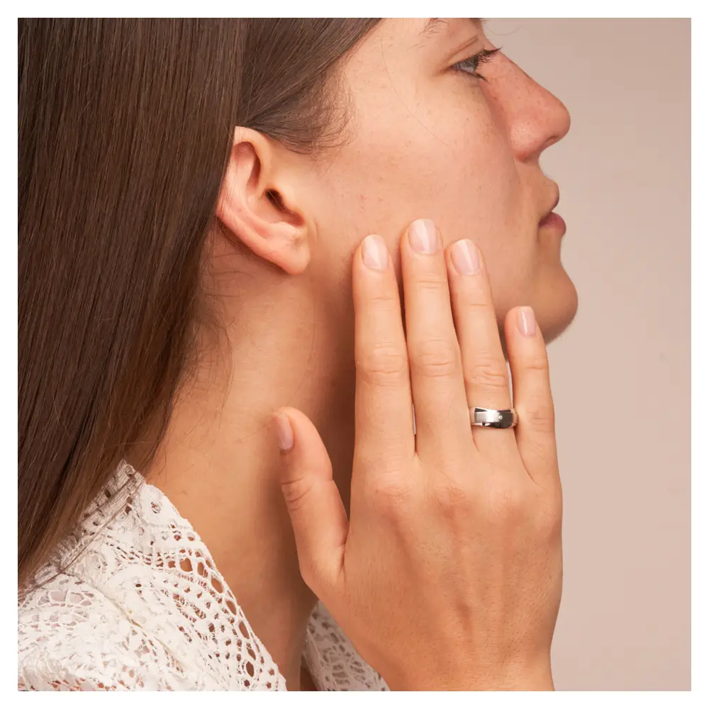 Trauringe aus Silber 925 platiniert mit welligem Rand und Diamant auf Hand am Gesicht