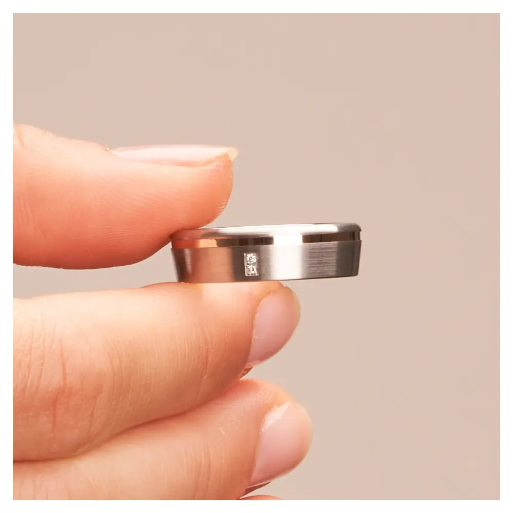 Eheringe aus Silber 925 mit Rotgold Rille und zwei Diamanten in Hand im Zoom