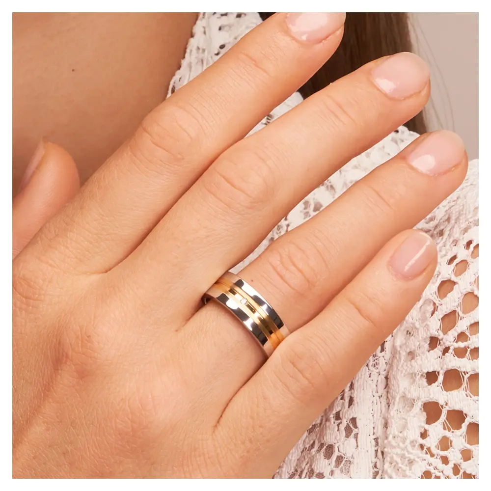 Trauringe aus Silber 925 platiniert mit 14K Gelbgold und Diamanten auf Hand am Gesicht im Zoom