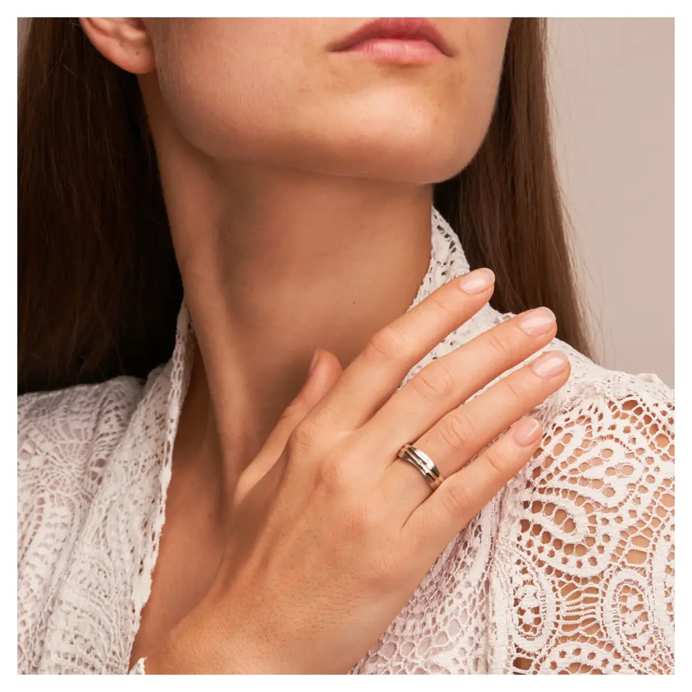 Eheringe aus platiniertem Silber 925 mit Diamanten und 14K Gelbgold Streifen auf Hand im Gesicht