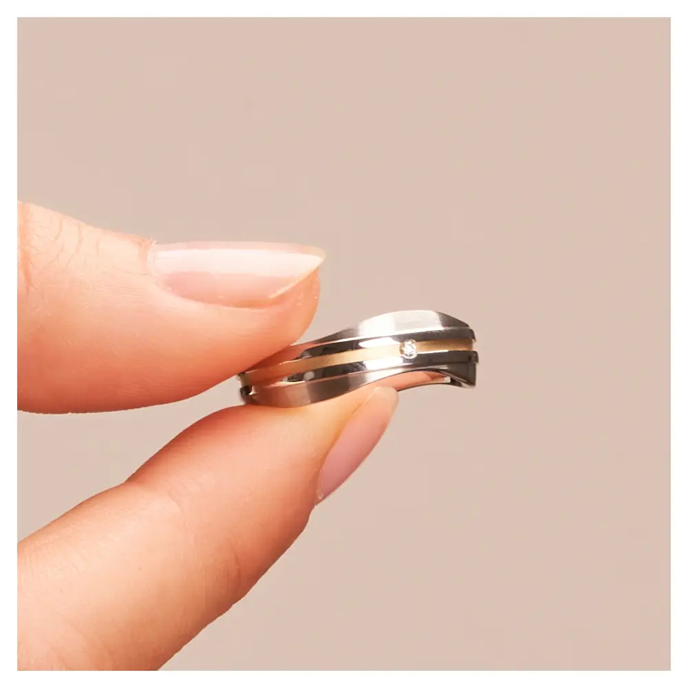 Eheringe aus platiniertem Silber 925 mit Diamanten und 14K Gelbgold Streifen in Hand im Zoom