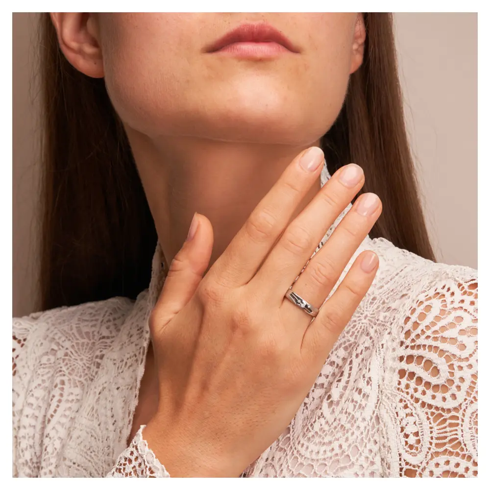 Trauringe aus platiniertem Silber 925 mit 3 Diamanten und geschwungenen Rillen auf Hand im Gesicht