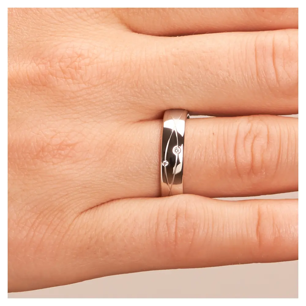 Eheringe aus platiniertem Silber 925 mit Rillenmuster und zwei Diamanten auf Hand im Zoom