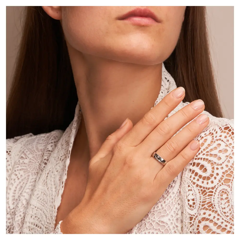 Eheringe aus platiniertem Silber 925 mit Rillenmuster und zwei Diamanten auf Hand am Gesicht