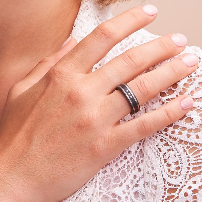Aufnahme von Trauringe aus Carbon mit zwei Streifen aus Palladium 500 und Diamanten auf Hand