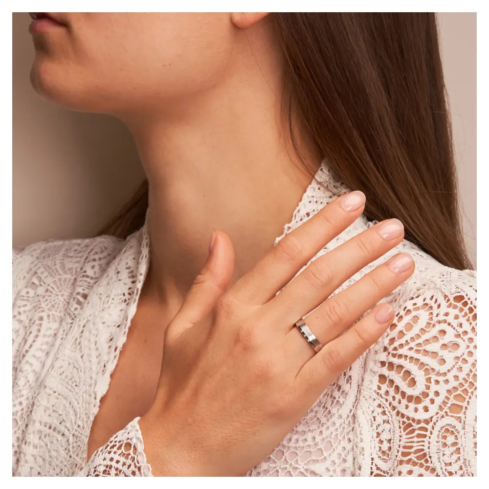 Trauringe aus Silber 925 platiniert mit drei Diamanten und Streifenmuster auf Hand im Gesicht