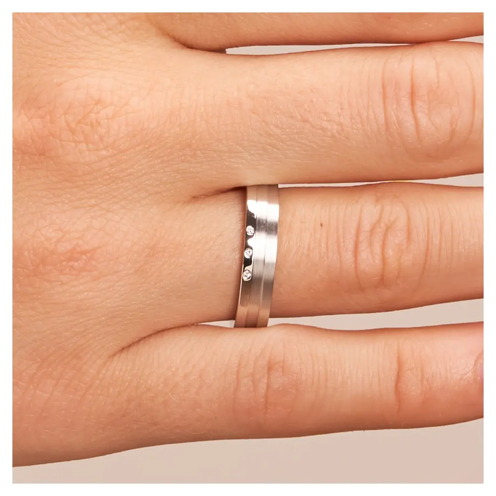 Trauringe aus Silber 925 platiniert mit drei Diamanten und Streifenmuster auf Hand im Zoom