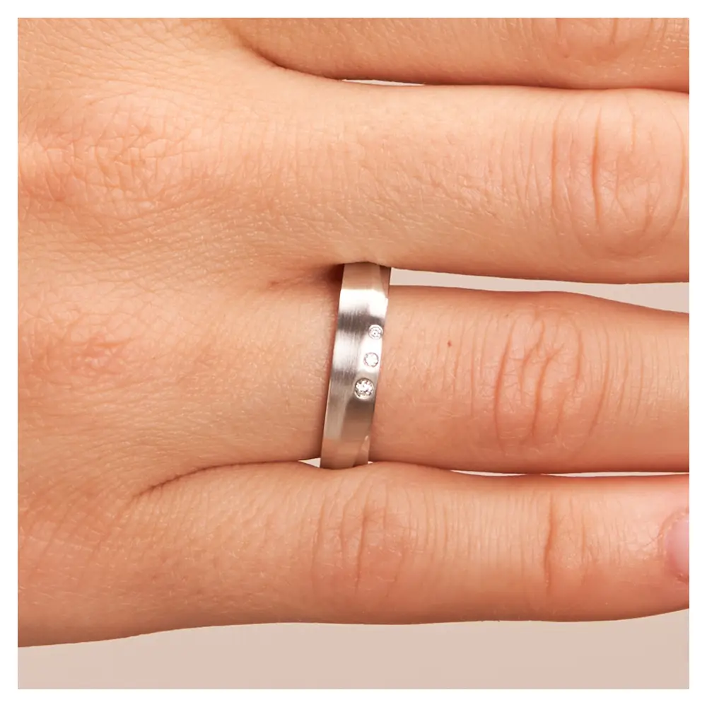 Eheringe aus Silber platiniert 925 längsmattiert strukturiert mit drei Diamanten auf Hand im Zoom