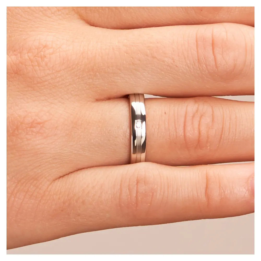 Trauringe aus Silber 925 platiniert mit polierten Rändern und Diamanten auf Hand im Zoom