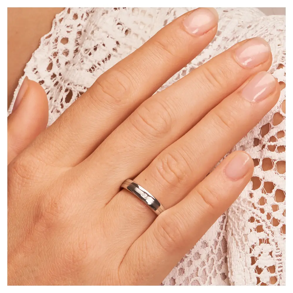 Trauringe aus Silber 925 platiniert mit polierten Rändern und Diamanten auf Hand am Gesicht im Zoom