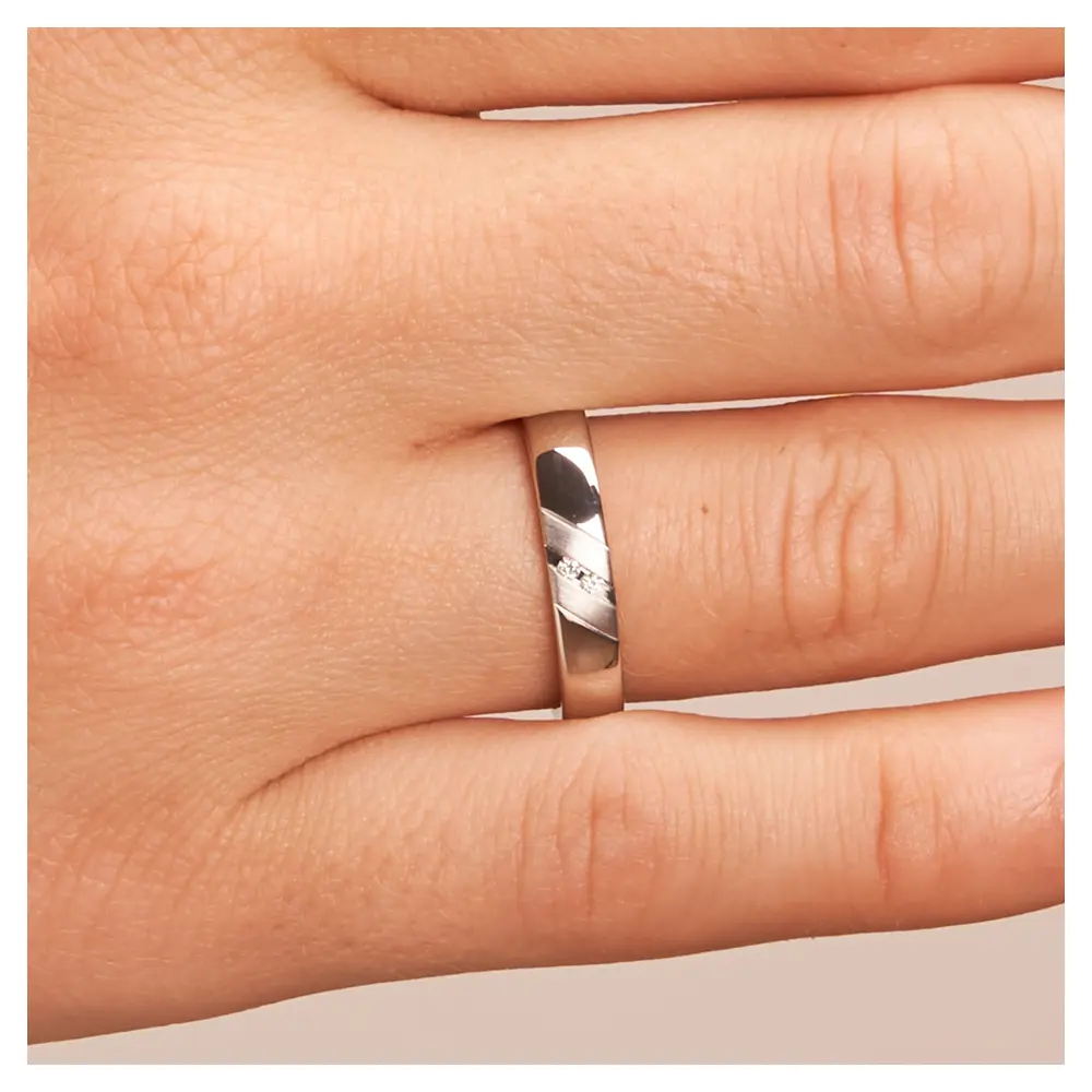 Polierte Eheringe aus 925 Silber mit zwei Diamanten und schrägen Rillen auf Hand im Zoom