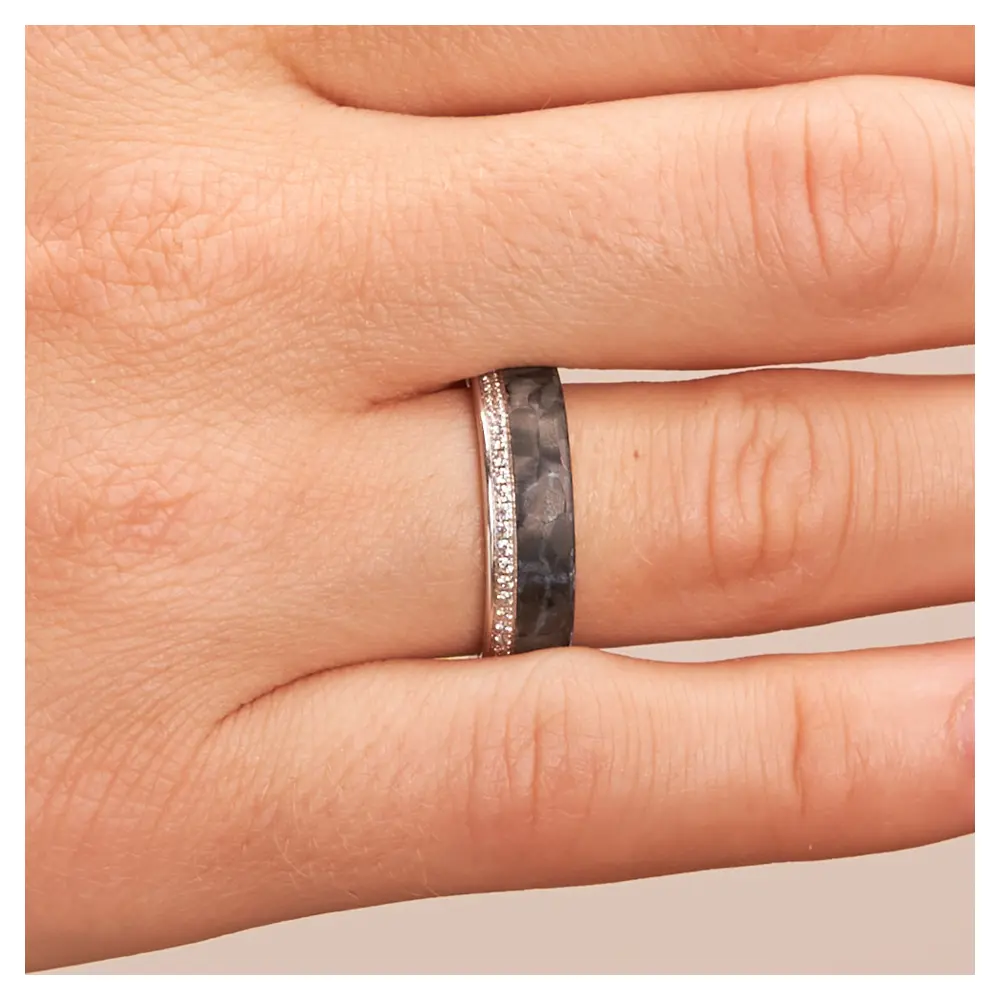 Eheringe aus poliertem Platin und mattem Carbon mit Diamantenband auf Hand im Zoom