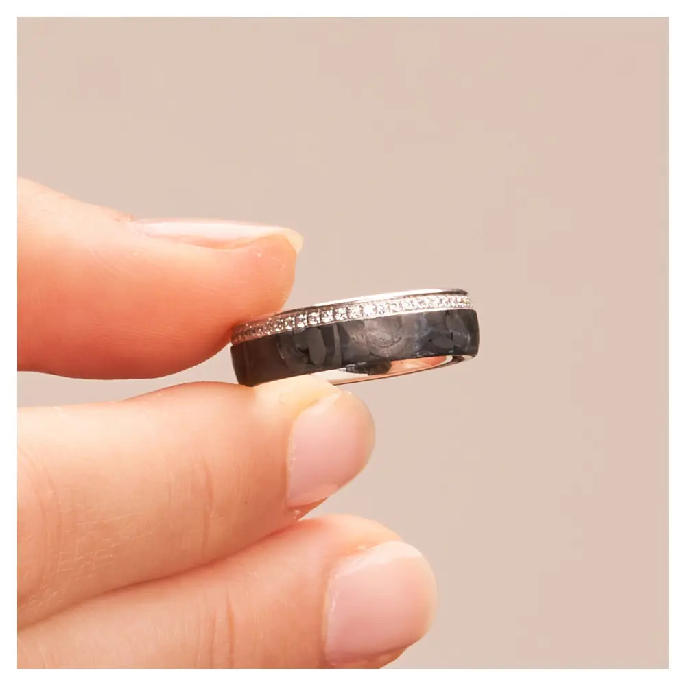 Eheringe aus poliertem Weißgold und mattem Carbon mit Diamantenband in Hand