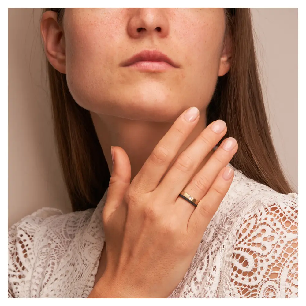 Matte Eheringe aus Roségold&Carbon mit Diamanten in 0,04 Karat auf Hand im Gesicht