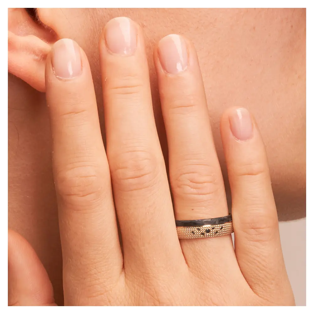 Eheringe aus Roségold und gemasertem Carbon mit schwarzen Diamanten auf Hand am Gesicht im Zoom