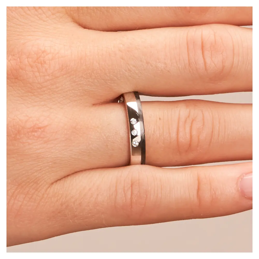 Polierte Eheringe aus Platin und Carbon mit seitlichem Muster und Diamanten auf Hand im Zoom