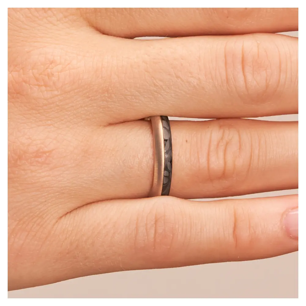 Eheringe aus Rotgold und Carbon mit Querbürstung auf Hand im Zoom