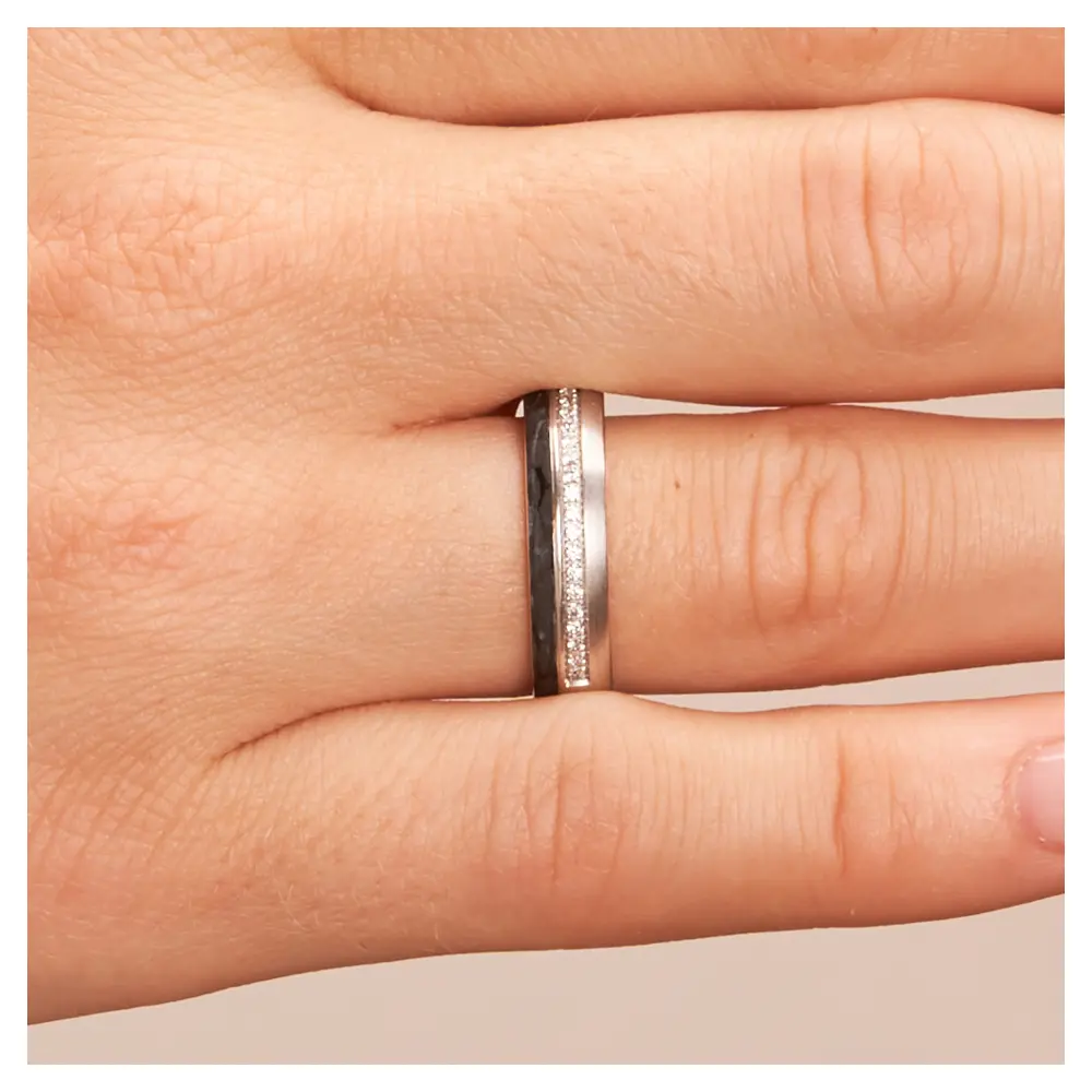 Eheringe aus Platin mit seitlichem Carbonstreifen und 20 Diamanten in Kanalfassung auf Hand im Zoom